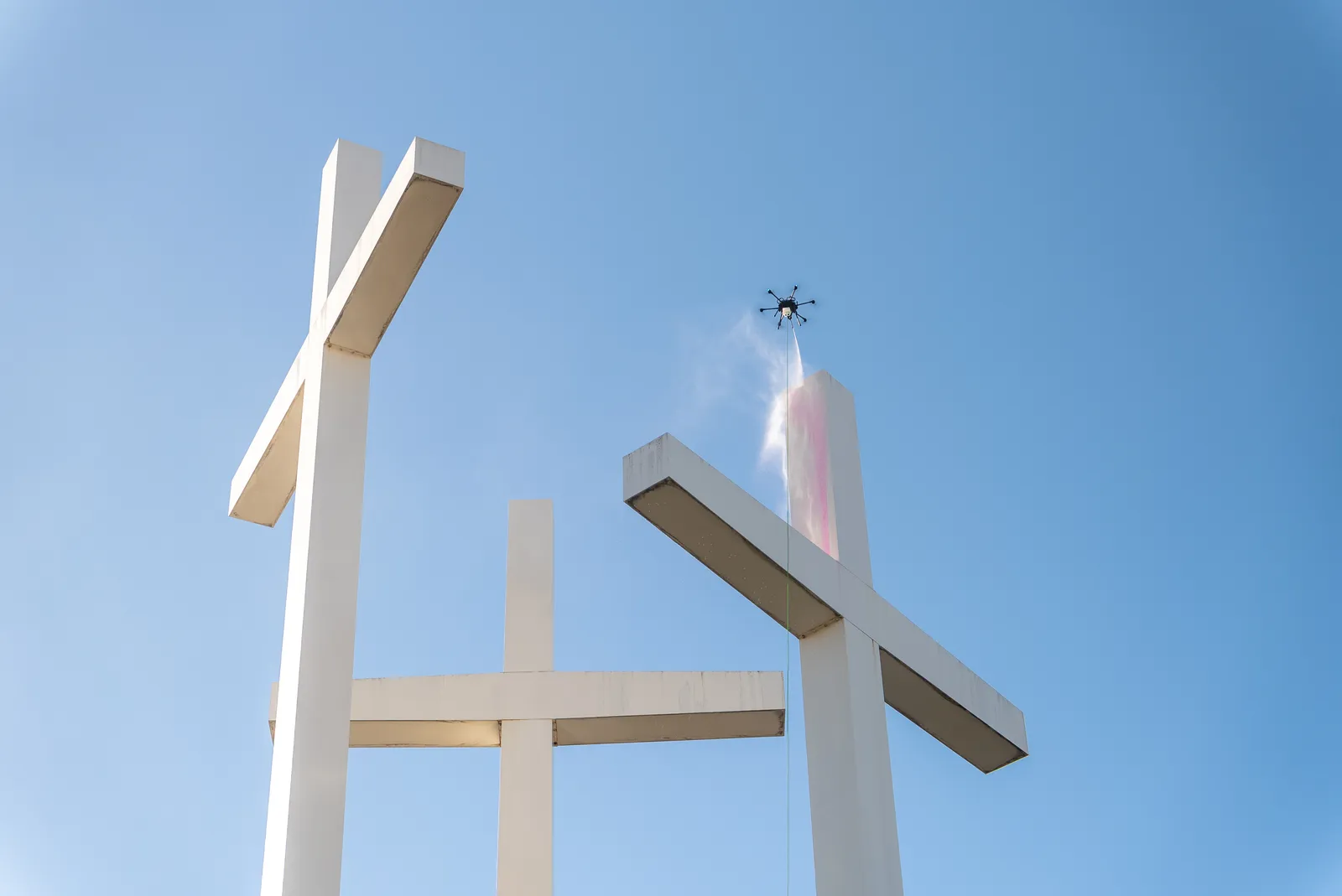 Lucid Bots Sherpa cleaning drone applying solution to tall white architectural elements